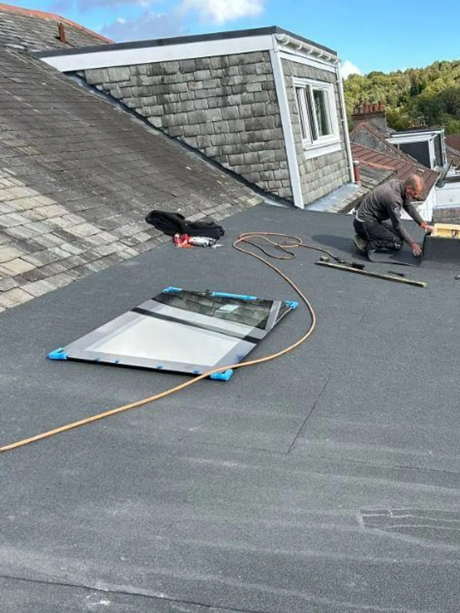 A roofer fitting a rooflight into a new flat felt roof