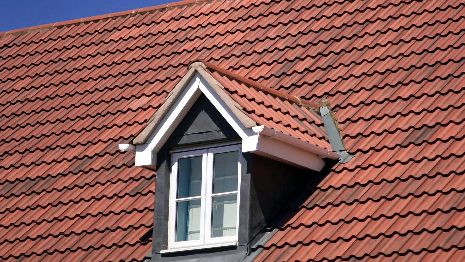 A red tiled roof with a white dormer window
