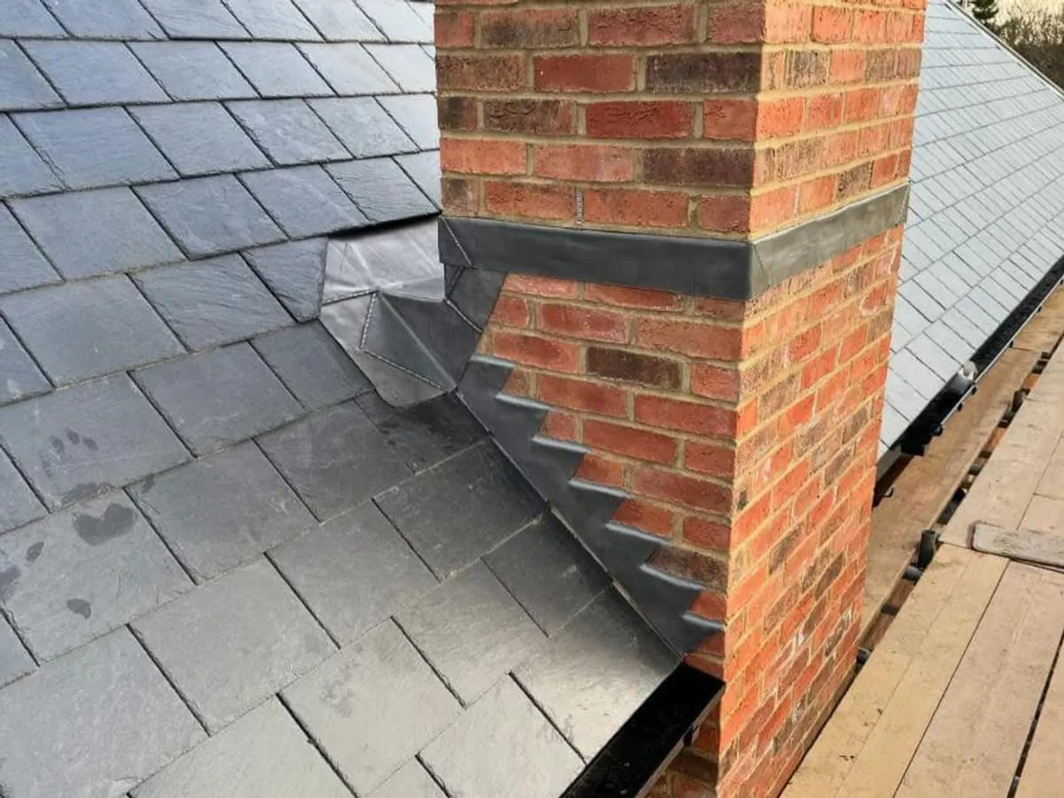 Lead flashing dressed in around a brick chimney on a slate roof