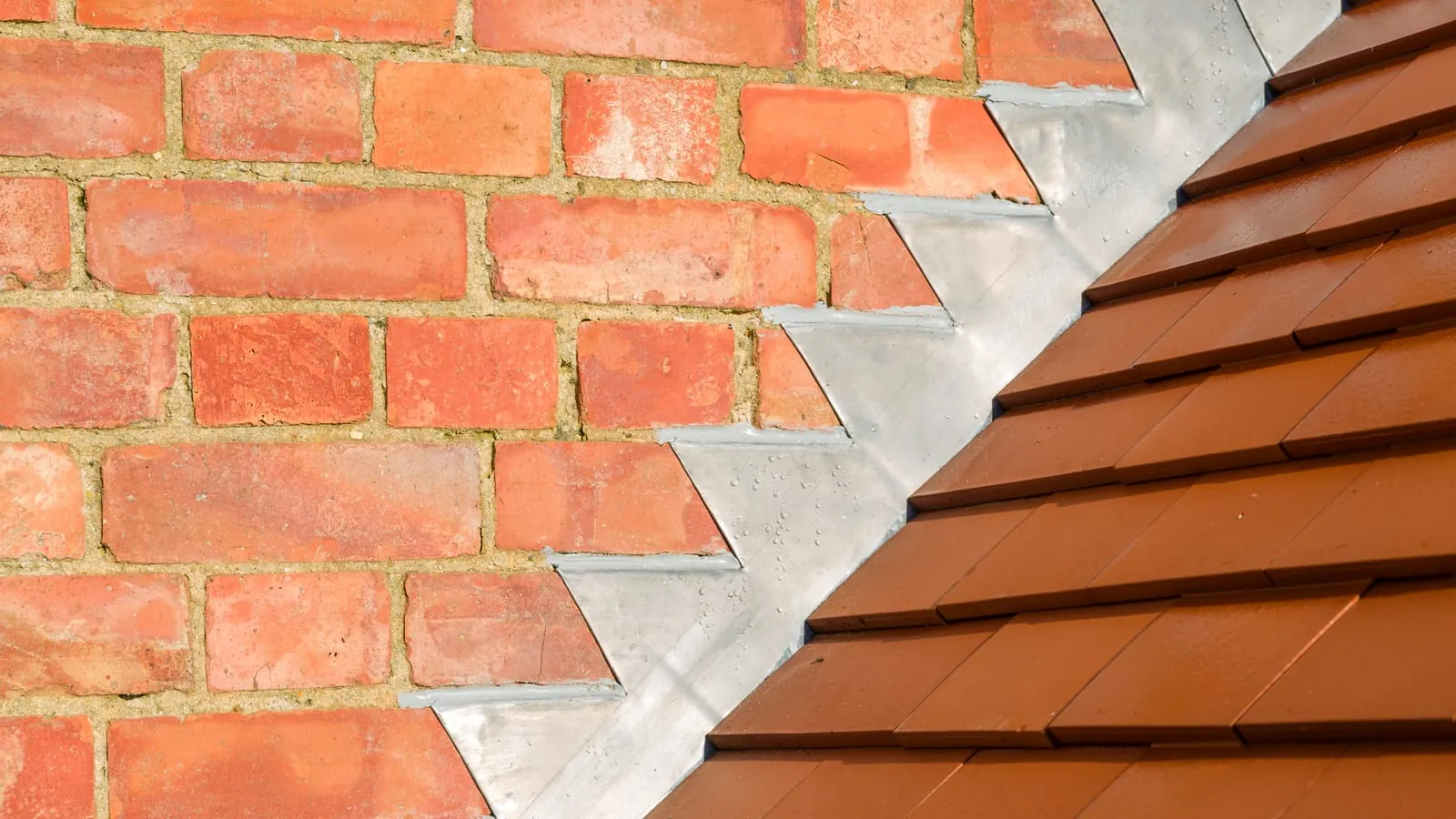 Stepped lead soakers dressed into the brickwork where a tiled roof meets a wall