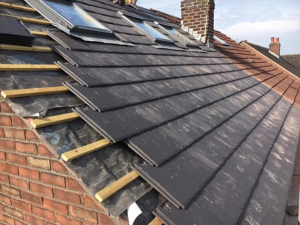 New slate being laid over fresh battens, with the rooflights already fitted