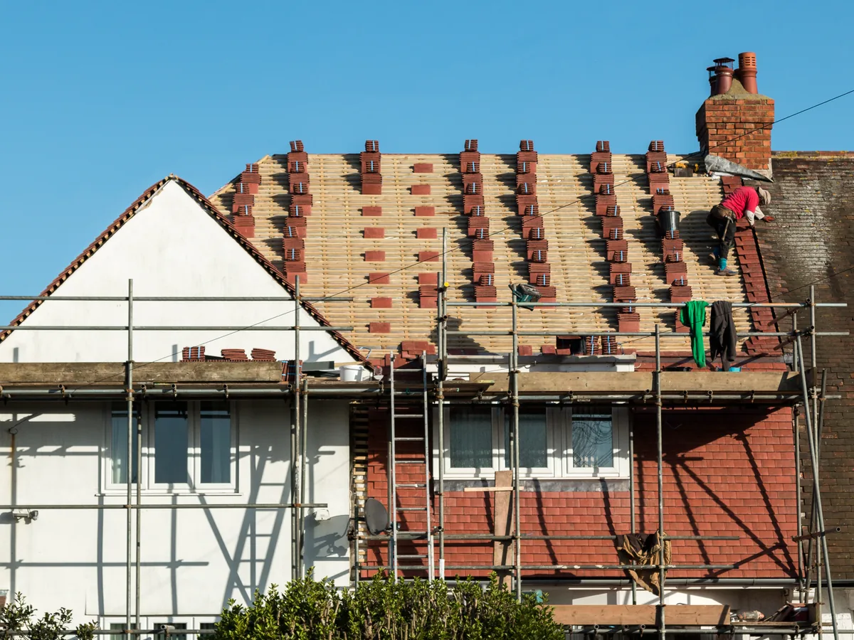 A damaged ridge on a tiled roof with tiles missing and the battens left open