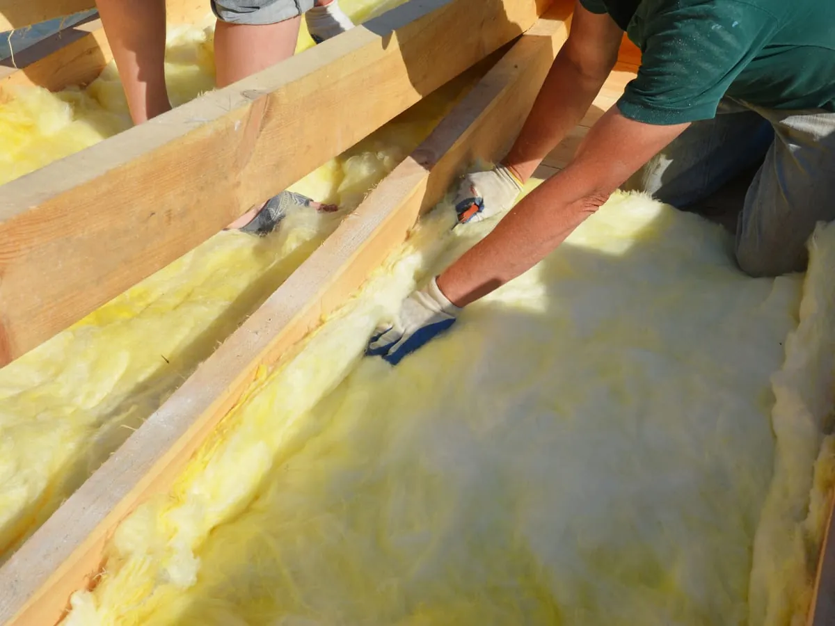 Mineral wool insulation being laid between the joists in a loft