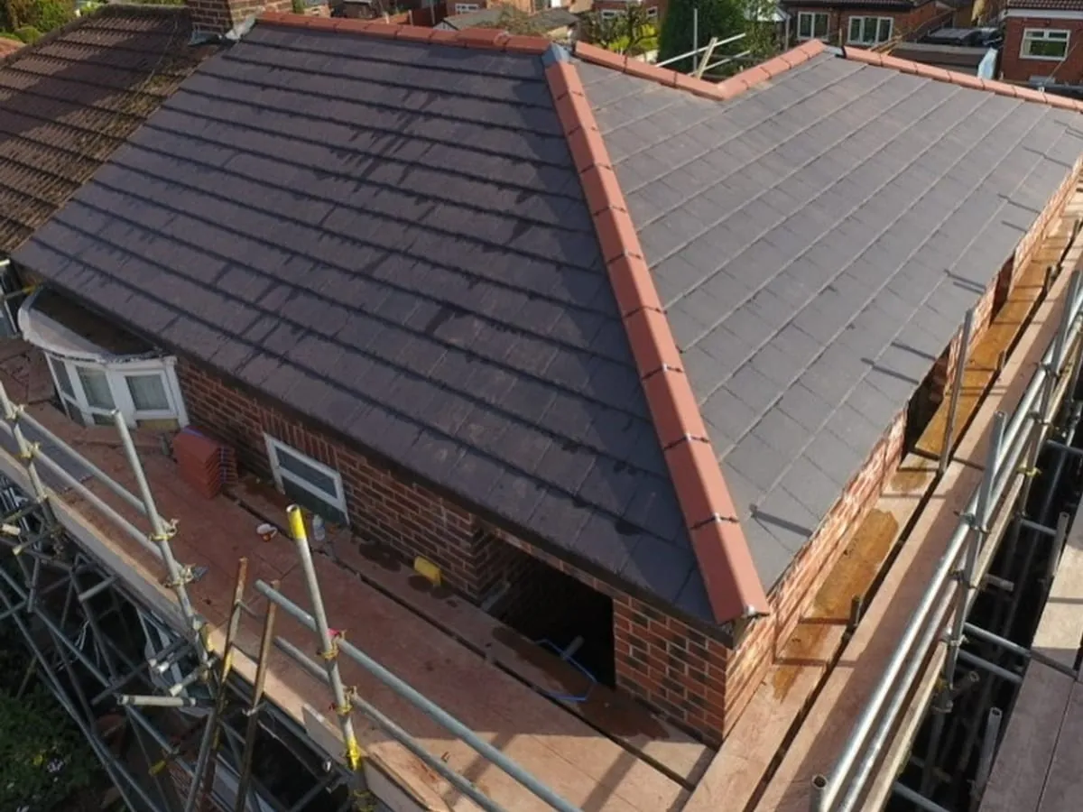 A finished tiled roof with a terracotta dry ridge and dry verge on a brick semi